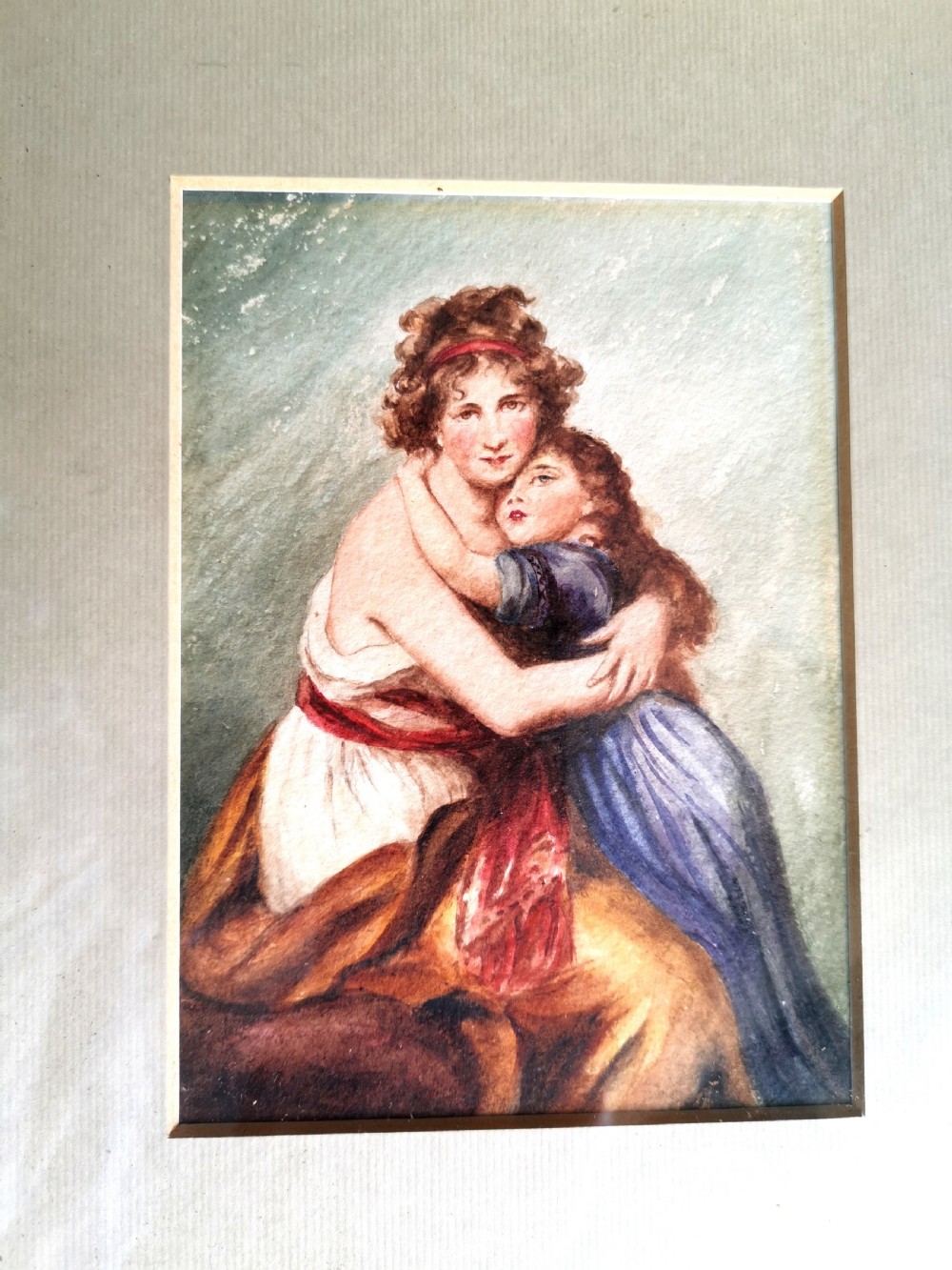A small 19th-century watercolour portrait depicting a mother embracing her young child set within a wide cream mount and a beaded gold gilt frame. View III