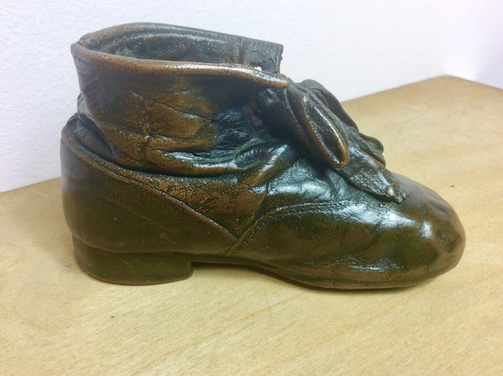 An early twentieth-century infant leather shoe preserved with an electroplated copper coating, featuring tied laces and creased detail. View II