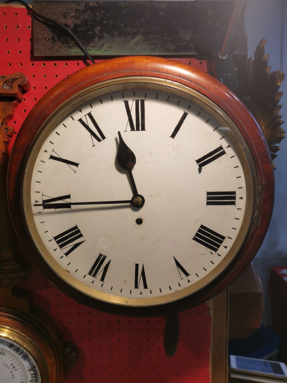 A circular nineteenth-century wall clock featuring a turned mahogany frame, a brass bezel, and a white dial with black Roman numerals.