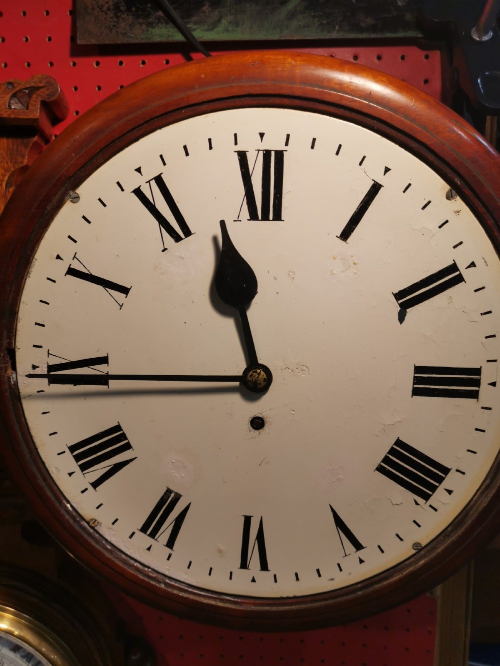 A circular nineteenth-century wall clock featuring a turned mahogany frame, a brass bezel, and a white dial with black Roman numerals. View II