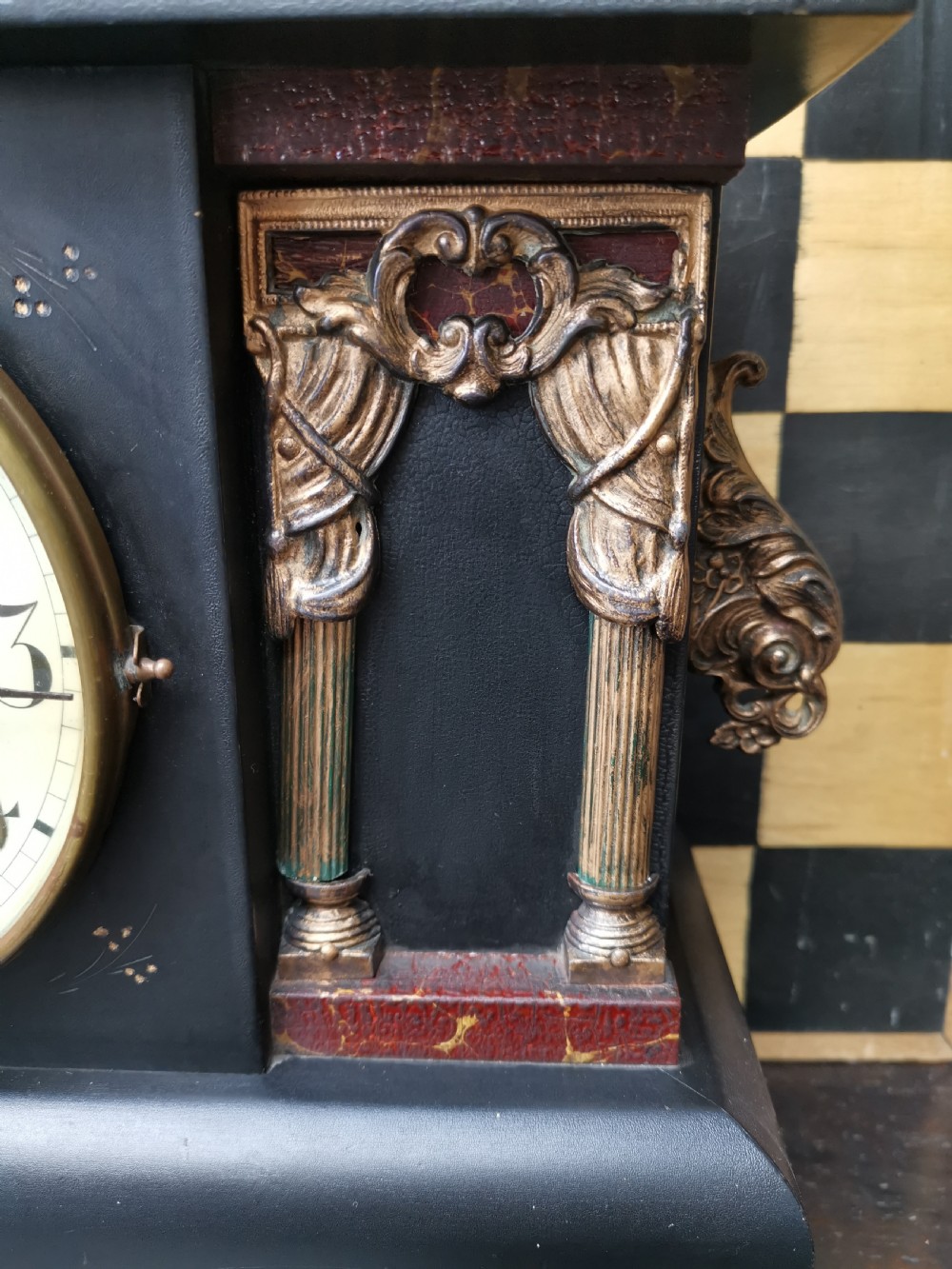 An antique late 19th-century ebonised black wooden mantel clock featuring a serpentine shaped top, gilt metal architectural columns, and ornate scroll feet. View II