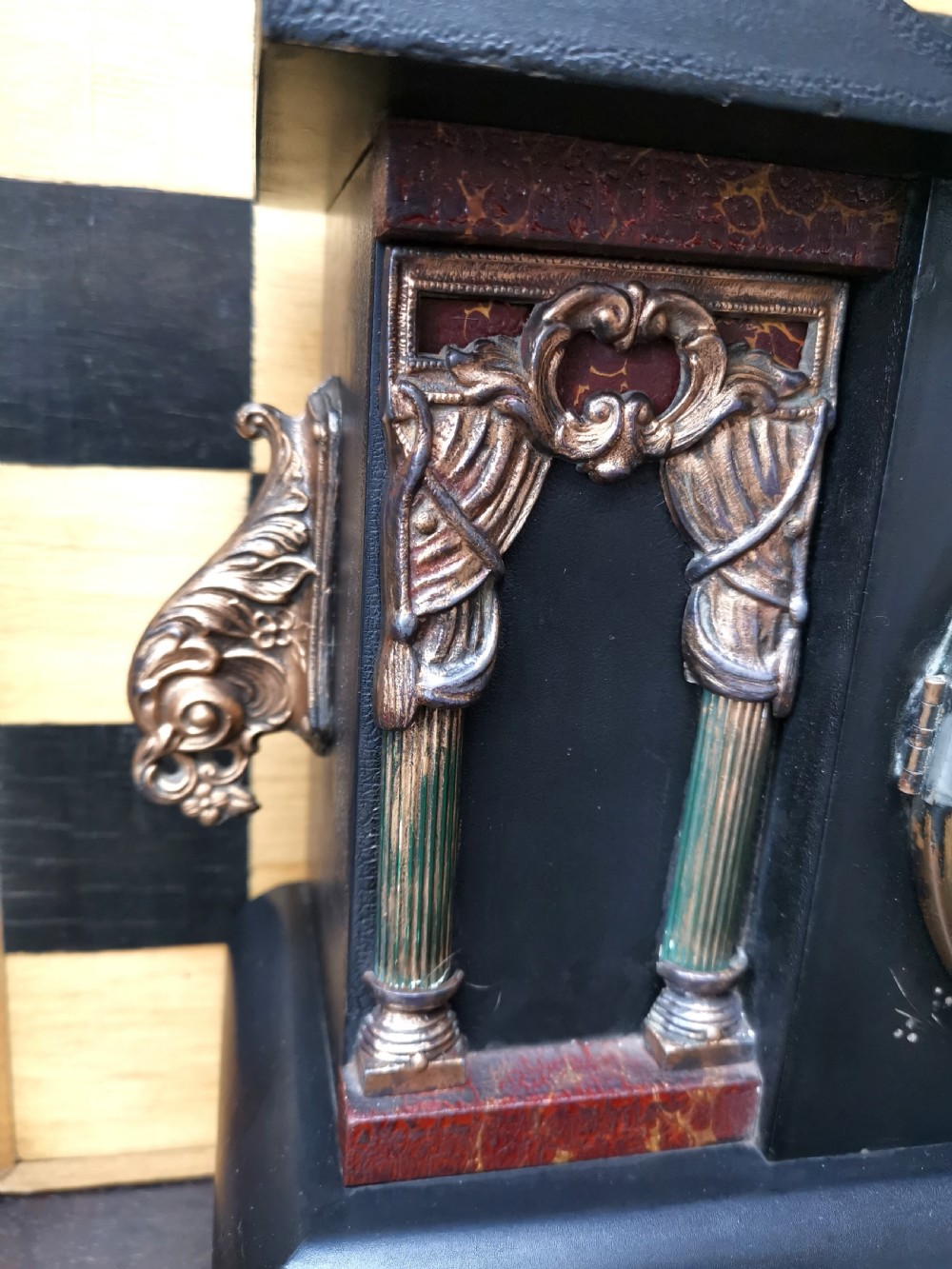 An antique late 19th-century ebonised black wooden mantel clock featuring a serpentine shaped top, gilt metal architectural columns, and ornate scroll feet. View III