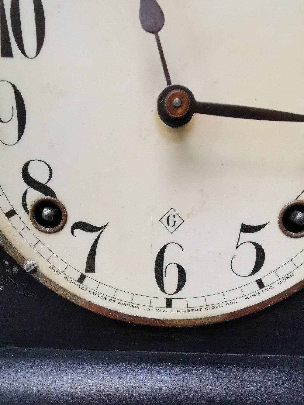 An antique late 19th-century ebonised black wooden mantel clock featuring a serpentine shaped top, gilt metal architectural columns, and ornate scroll feet. View IV