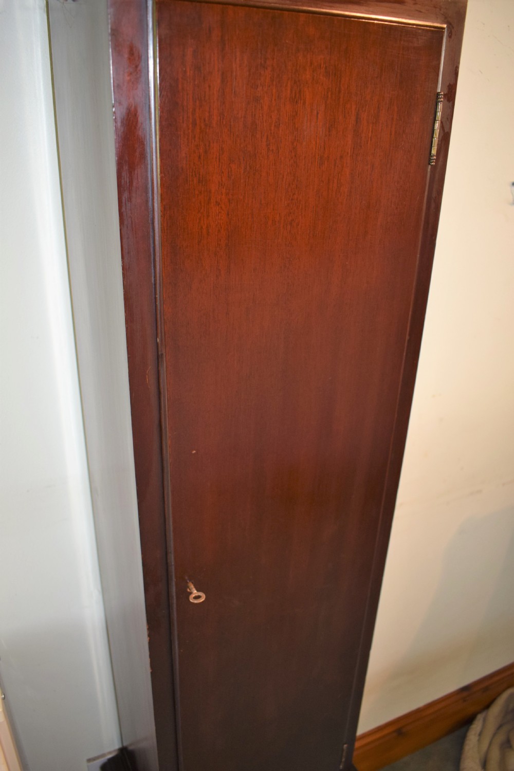 An antique dark mahogany longcase clock featuring an arched hood, engraved silvered dial with Roman numerals, and side fretwork sound apertures. View IV