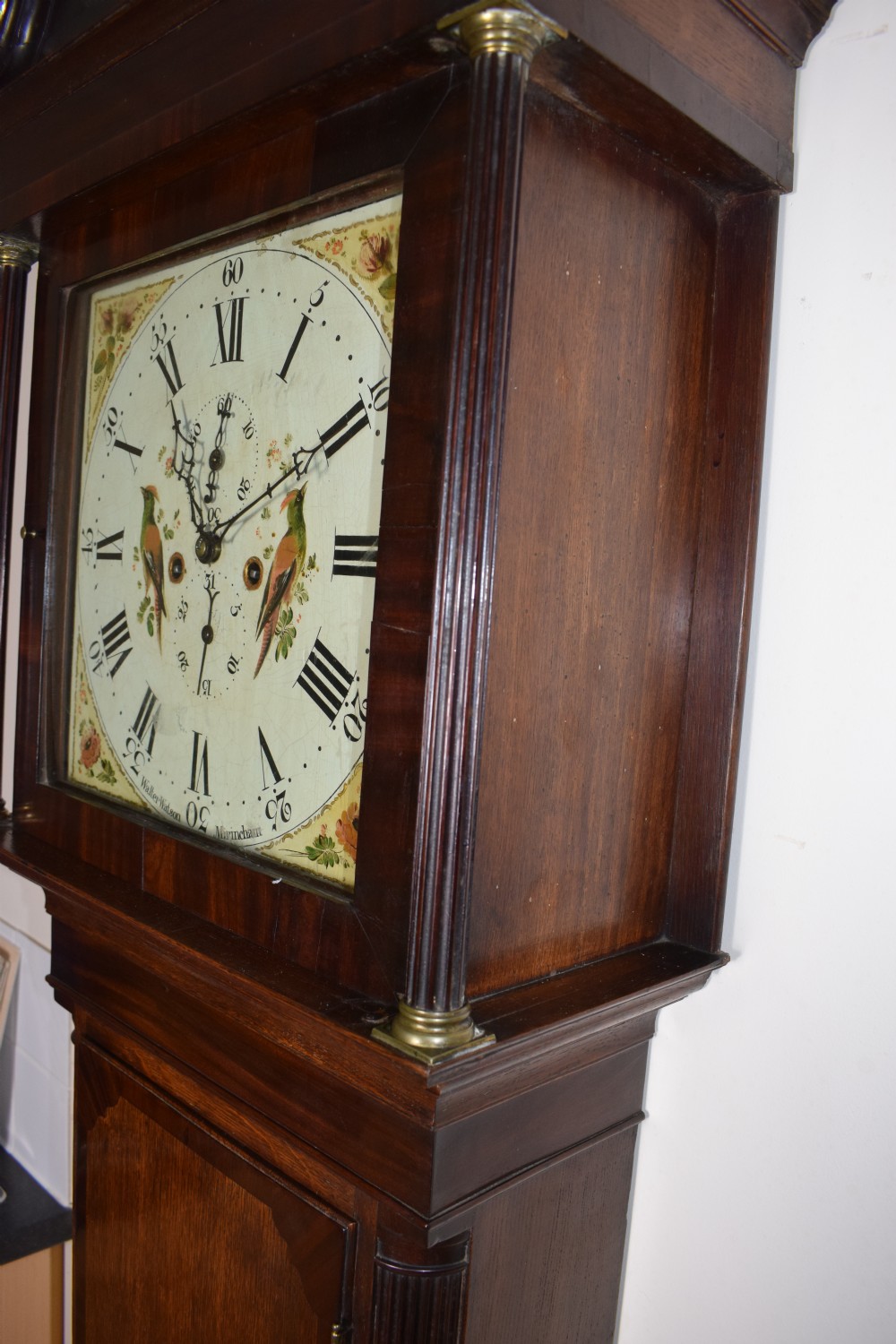 A Georgian oak and mahogany crossbanded longcase clock featuring a swan-neck pediment, brass finials, reeded columns, and a hand-painted dial with bird decoration. View V