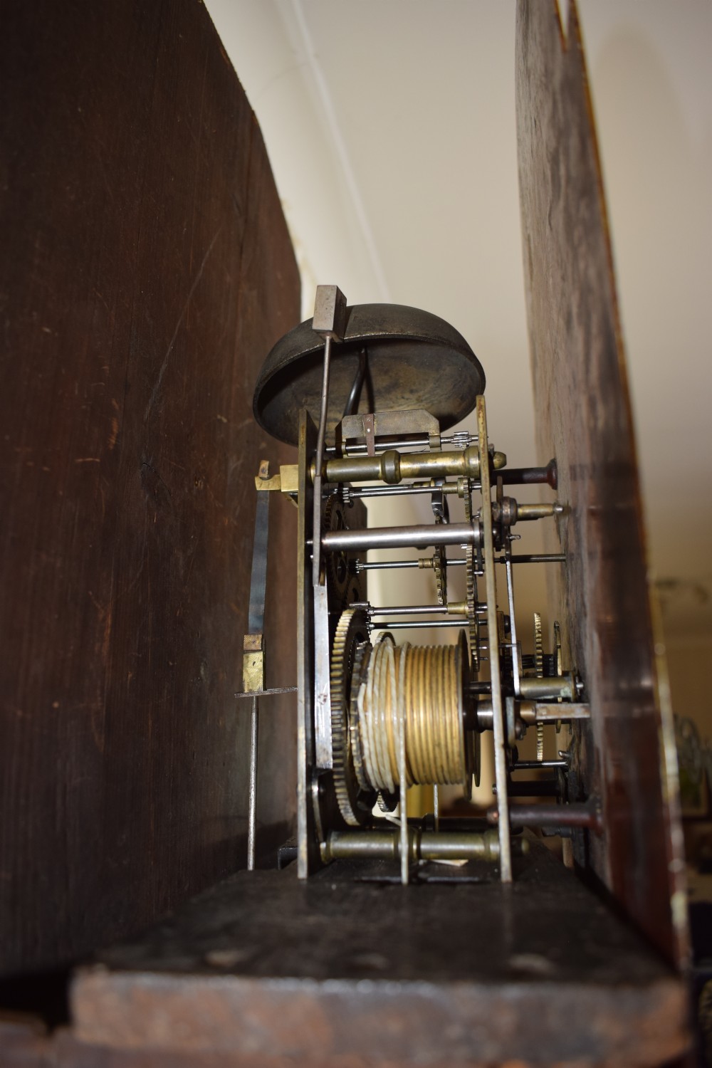 An early 19th-century Georgian flame mahogany longcase clock featuring a swan-neck pediment, brass patera, turned columns, and a hand-painted dial depicting a pastoral scene with Roman numerals. View XV