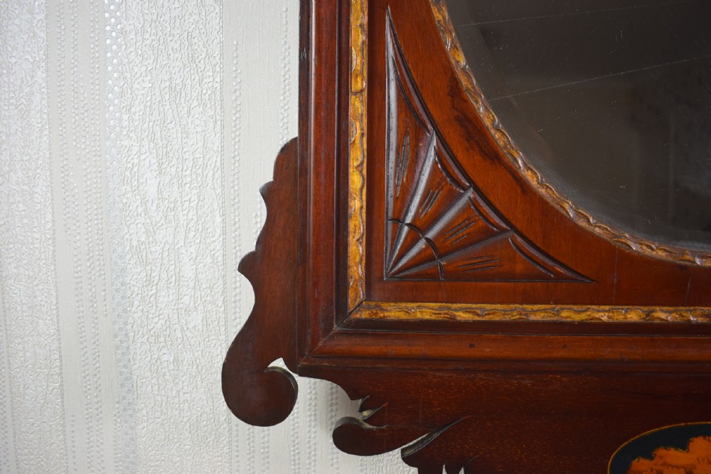 A 19th-century mahogany wall mirror featuring a bevelled oval glass plate, scroll fretwork border, gilded urn finial, and shell marquetry inlay. View IV