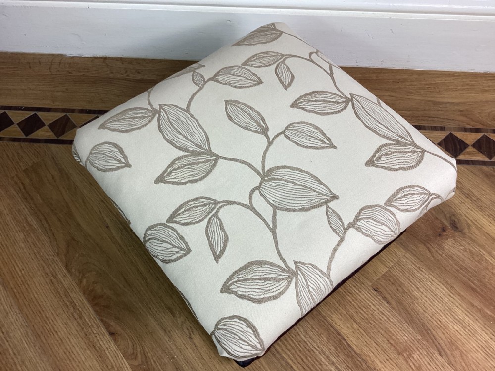 A square Victorian footstool featuring a dark mahogany plinth with turned bun feet and cream upholstery patterned with leaves. View IV