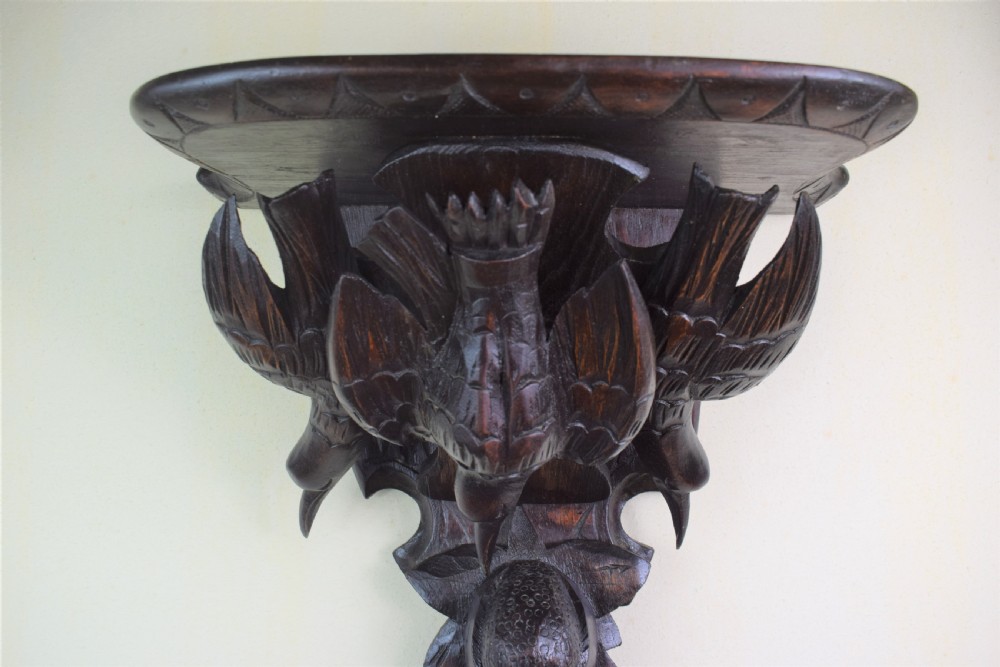 A close-up shot of a dark stained pine Black Forest wall bracket featuring intricately carved birds, fruit, and foliage. View VIII