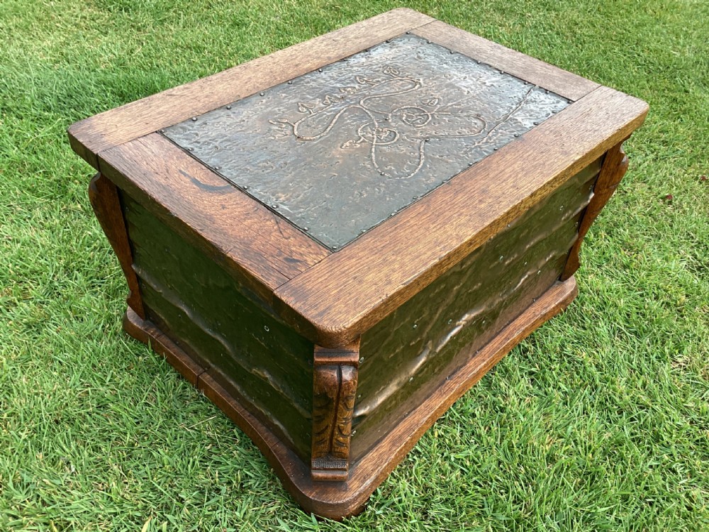 An Arts and Crafts oak log box featuring hammered copper panels with decorative repousse detailing and riveted edges. View II