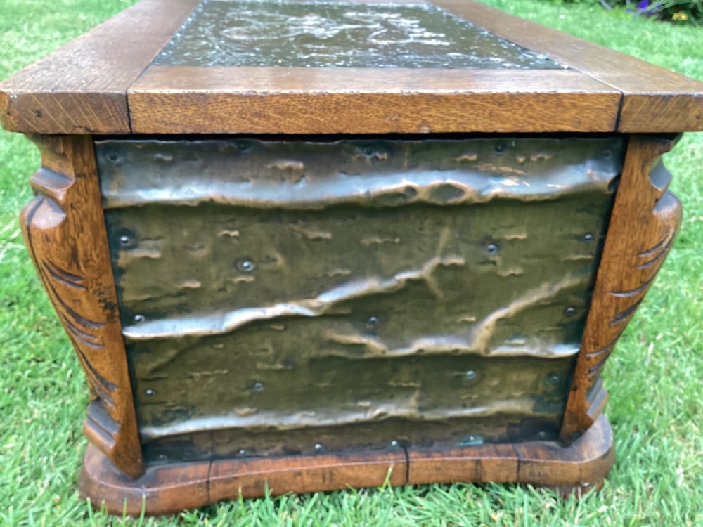 An Arts and Crafts oak log box featuring hammered copper panels with decorative repousse detailing and riveted edges. View X
