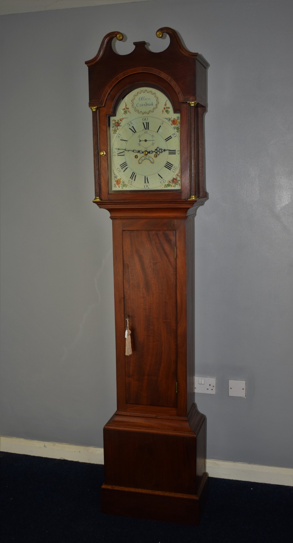 An early nineteenth-century Georgian mahogany longcase clock featuring a painted dial with floral spandrels and brass column mounts. View XIX