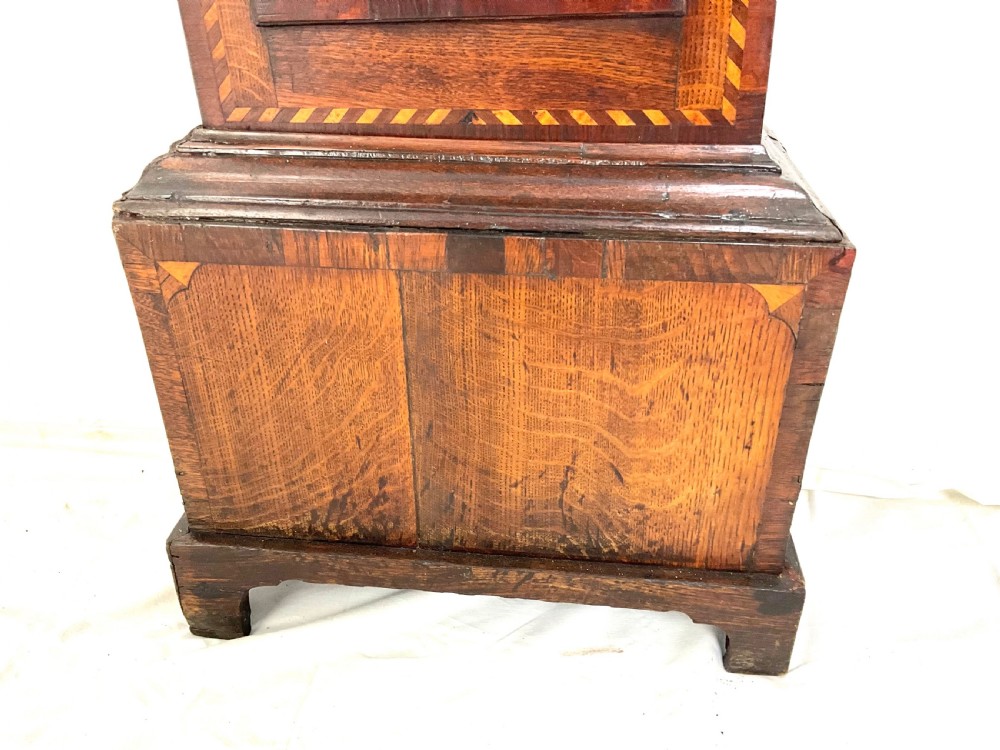 A Georgian oak longcase clock featuring a hand-painted arch dial, turned hood columns, and chequered geometric inlay. View VI