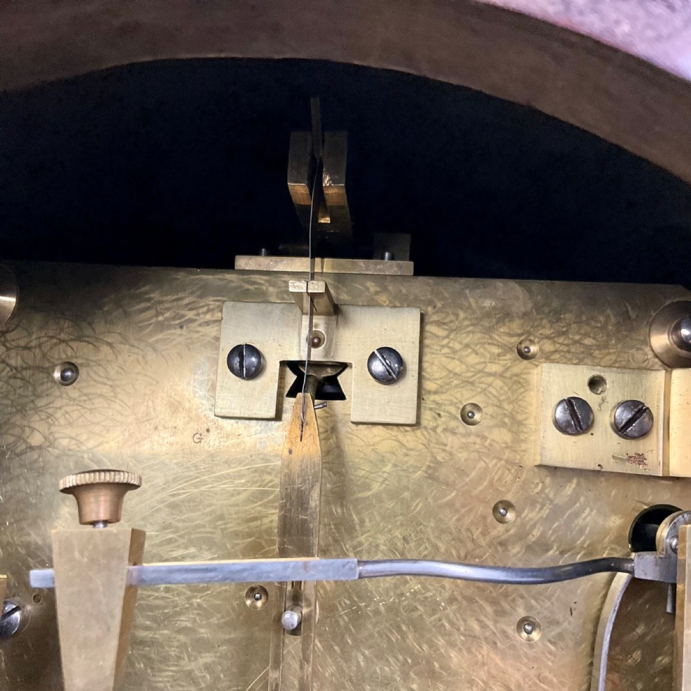 A 19th-century mahogany bracket clock featuring an arched top, brass-framed circular dial with Roman numerals, and brass turned feet. View VII