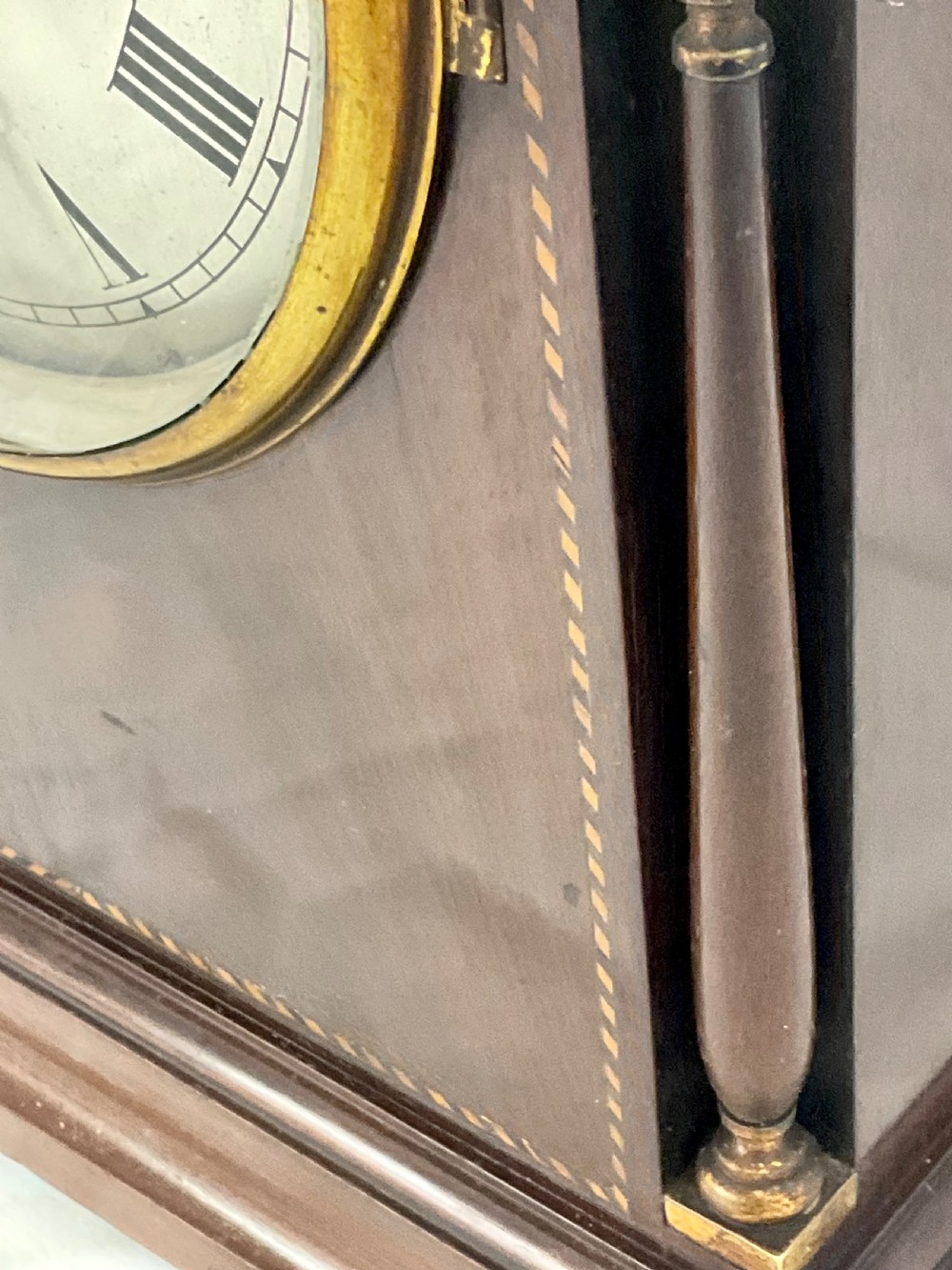 A 19th-century mahogany bracket clock featuring an arched top, brass-framed circular dial with Roman numerals, and brass turned feet. View XII