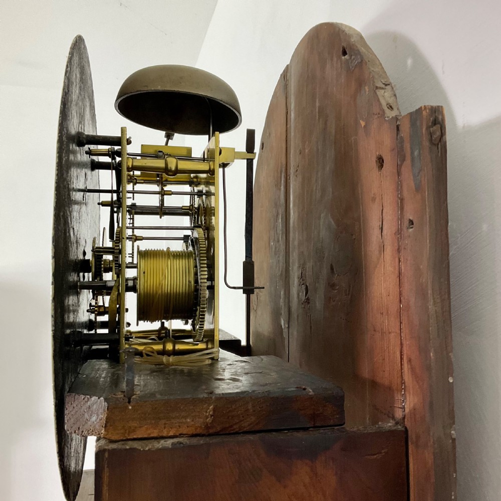 A Regency period flame mahogany longcase clock featuring a circular brass bezel, Roman numerals, subsidiary seconds display, and an arched bonnet. View XII