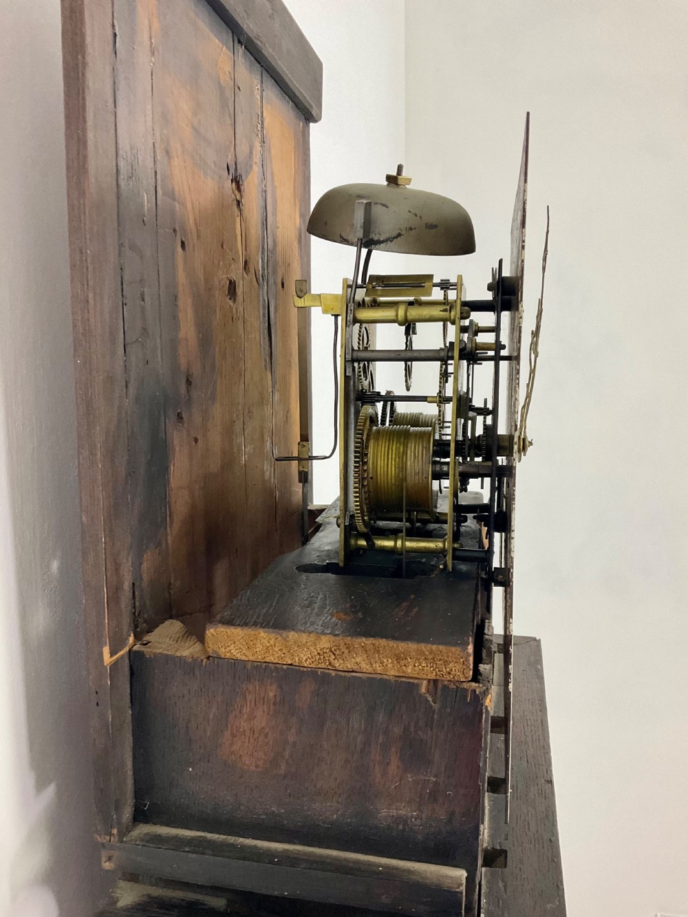 A tall Georgian oak longcase clock featuring a square painted dial, brass column accents, and a panelled wooden case. View X