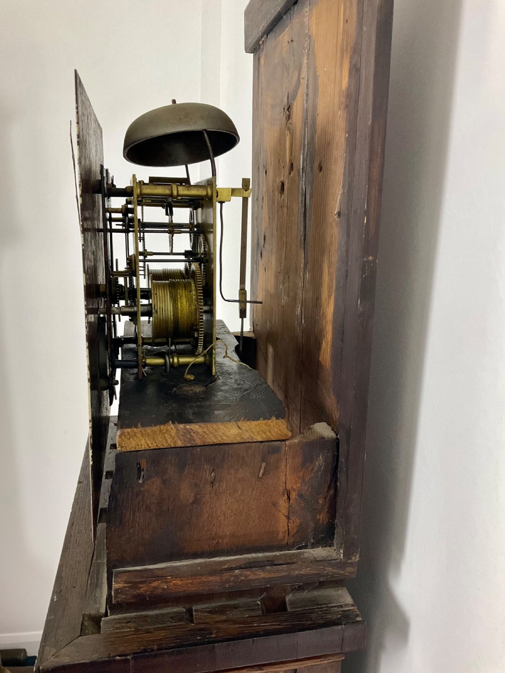 A tall Georgian oak longcase clock featuring a square painted dial, brass column accents, and a panelled wooden case. View XI