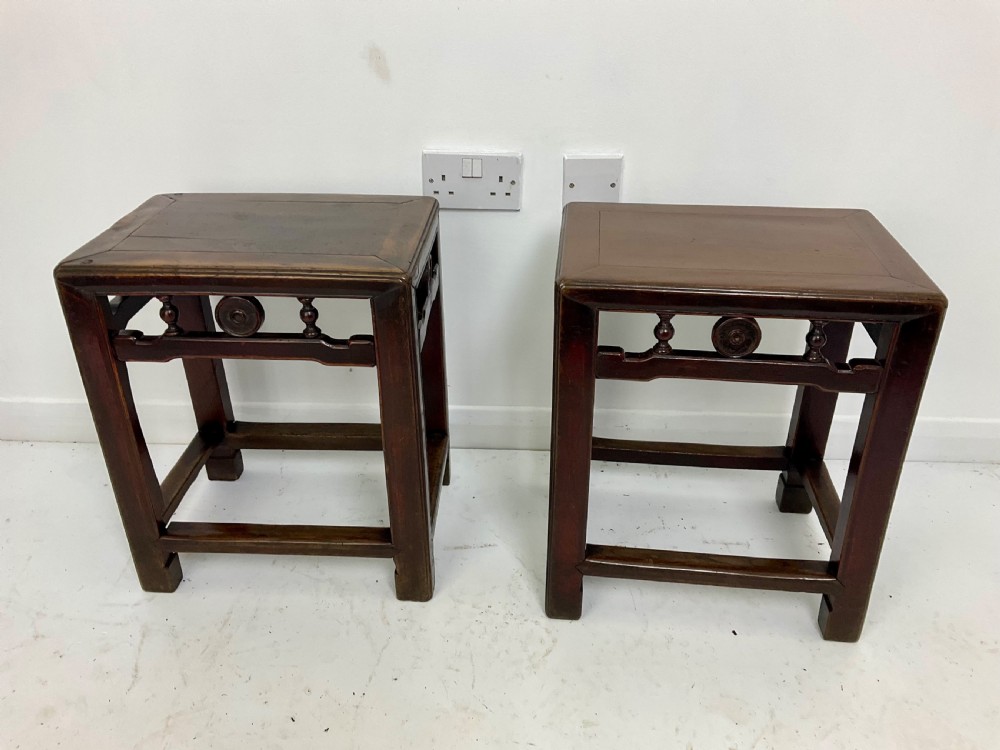 A pair of dark hardwood rectangular Chinese occasional tables featuring carved aprons with central circular medallions and turned baluster supports.