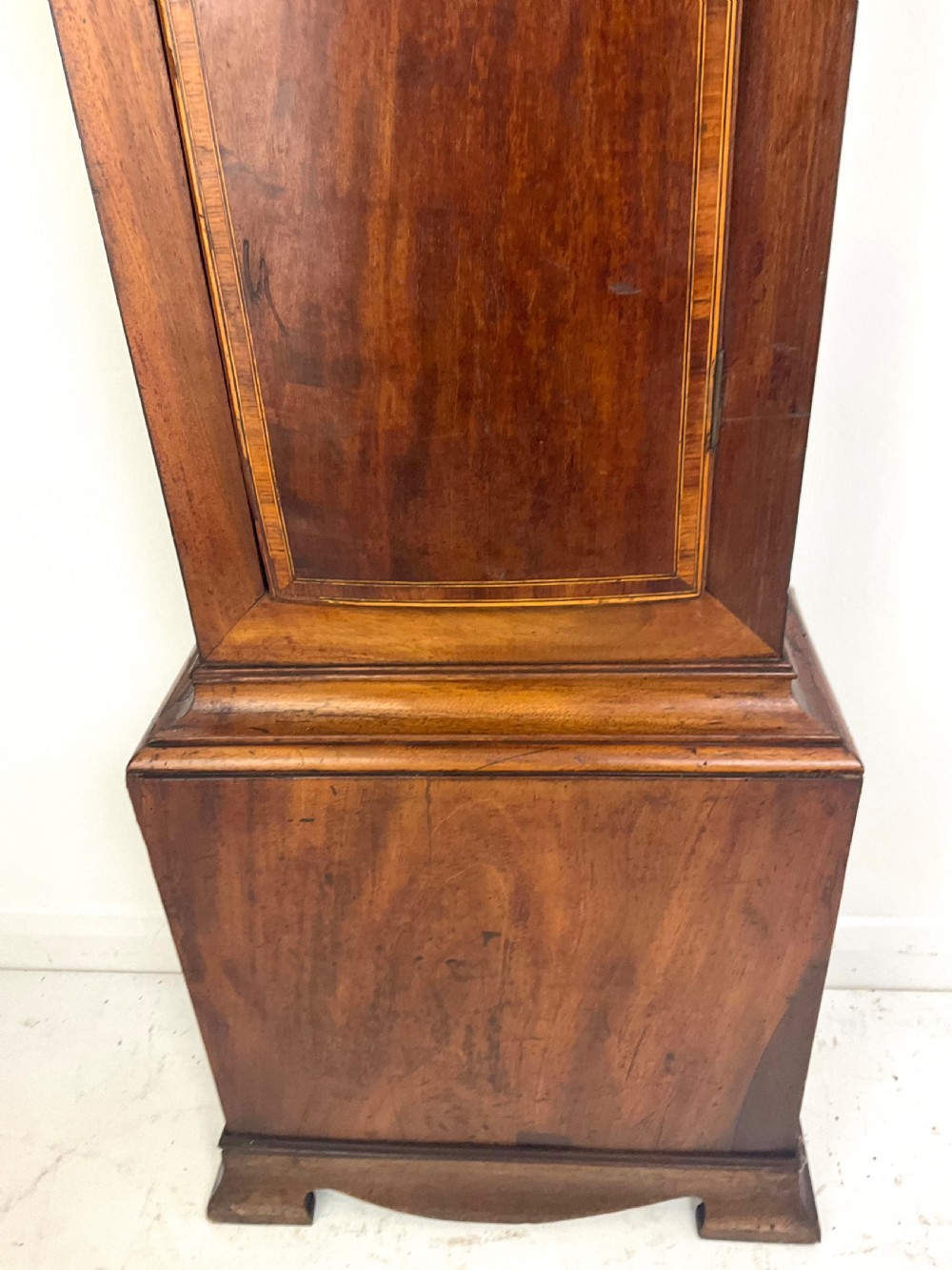 A Georgian mahogany longcase clock hood featuring a swan-neck pediment, brass eagle finial, reeded columns, and an engraved brass dial. View III