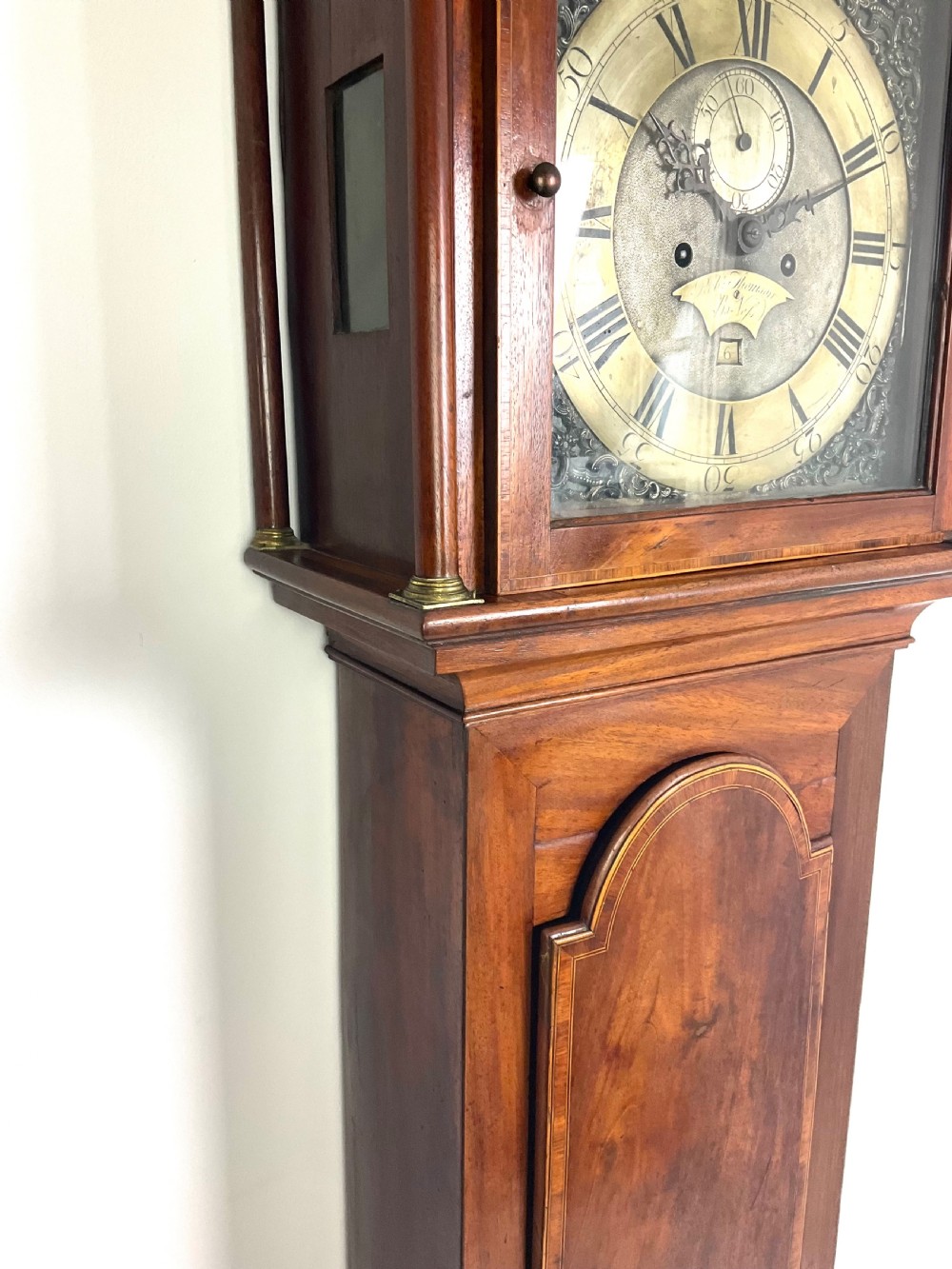 A Georgian mahogany longcase clock hood featuring a swan-neck pediment, brass eagle finial, reeded columns, and an engraved brass dial. View IV