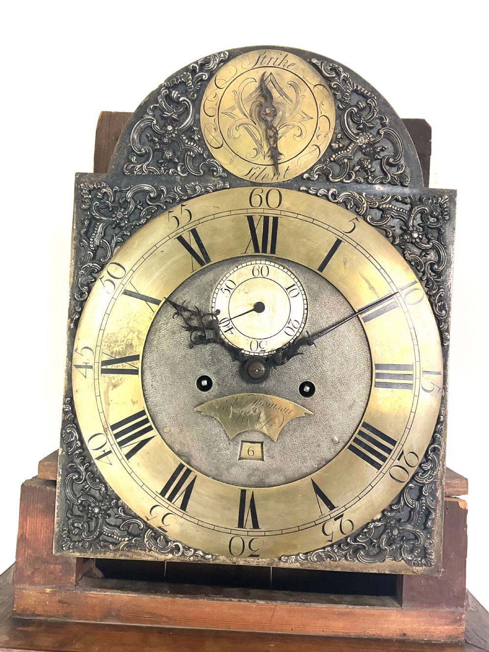 A Georgian mahogany longcase clock hood featuring a swan-neck pediment, brass eagle finial, reeded columns, and an engraved brass dial. View X