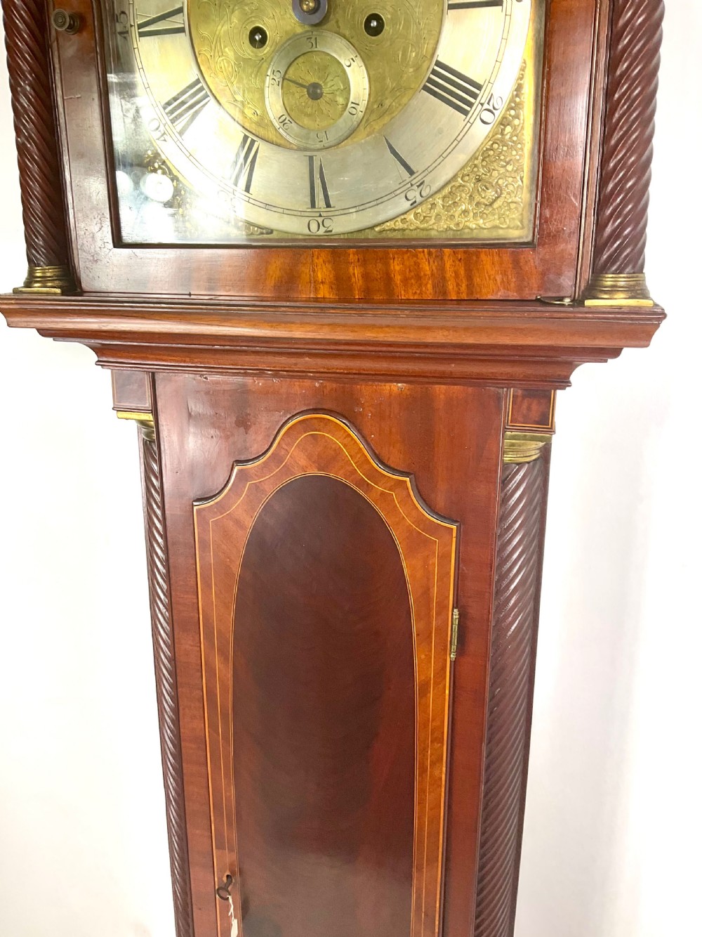 A late Georgian mahogany longcase clock featuring a swan-neck pediment, twisted columns, and an arched dial with silvered chapter ring. View II