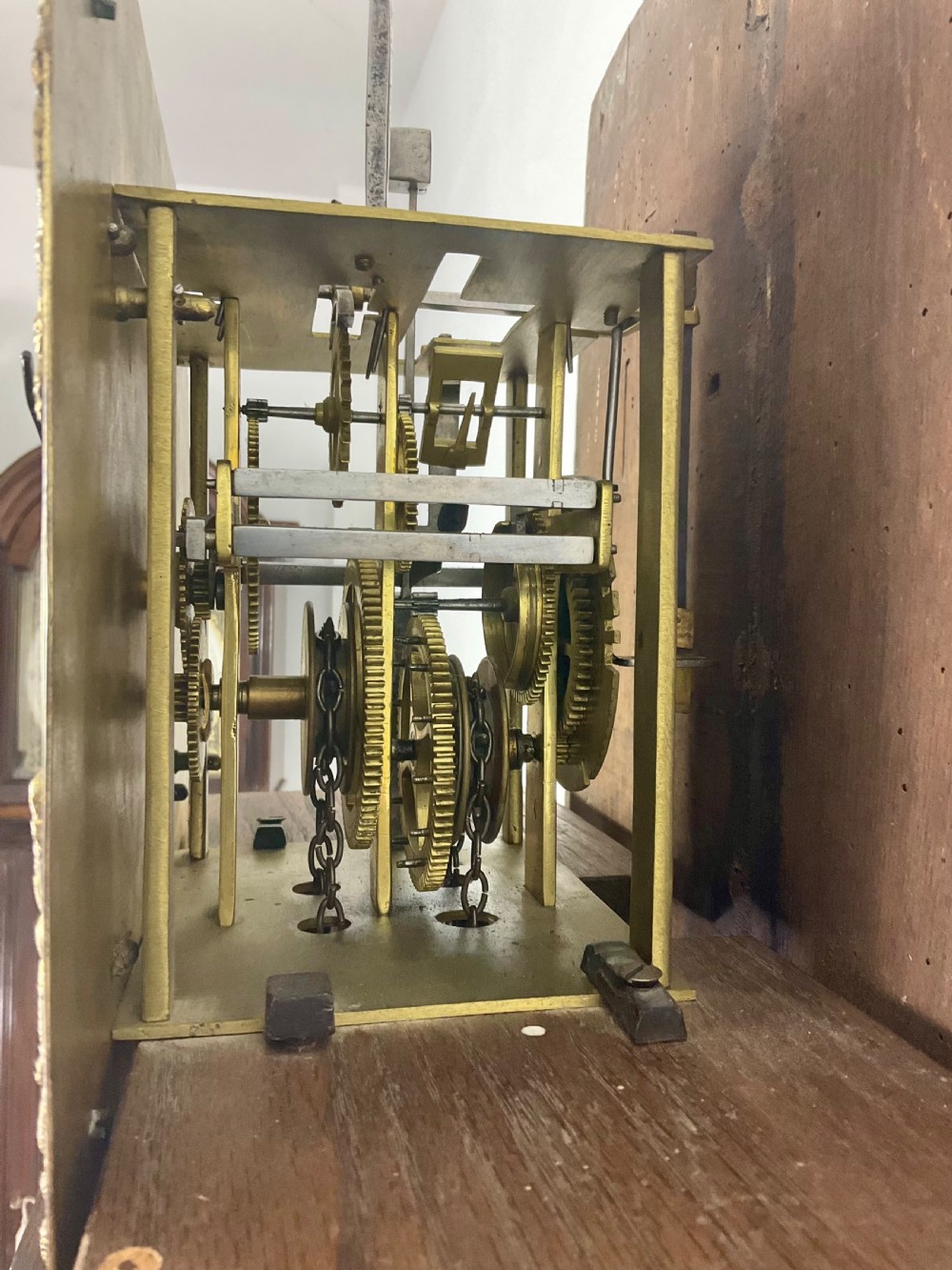 An antique Georgian oak longcase clock hood with a square brass dial, engraved numerals, corner spandrels, and turned side columns. View V