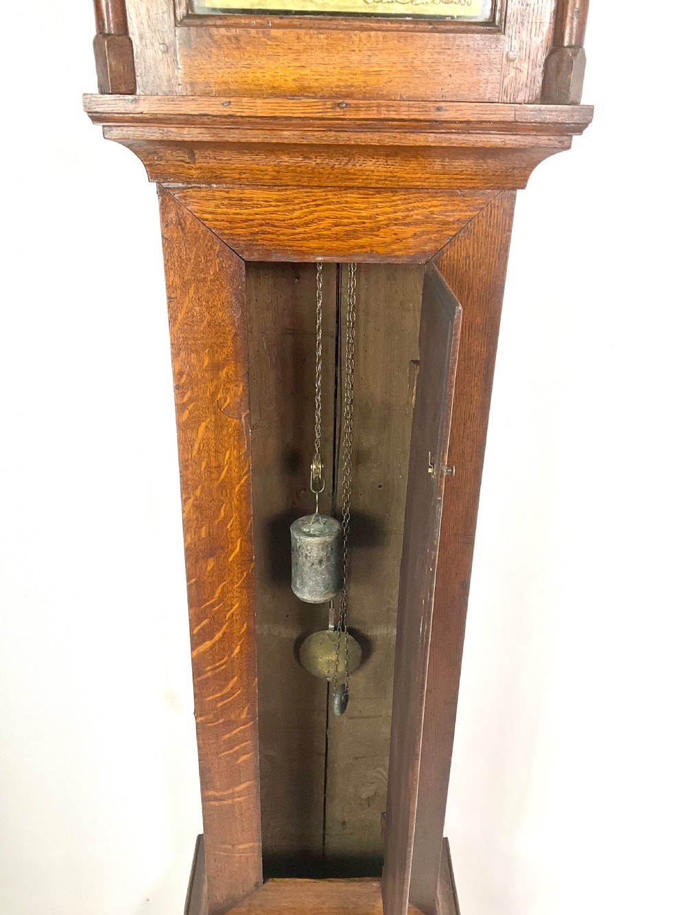 An antique Georgian oak longcase clock hood with a square brass dial, engraved numerals, corner spandrels, and turned side columns. View VIII