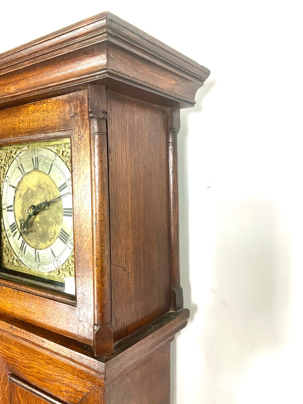 An antique Georgian oak longcase clock hood with a square brass dial, engraved numerals, corner spandrels, and turned side columns. View IX