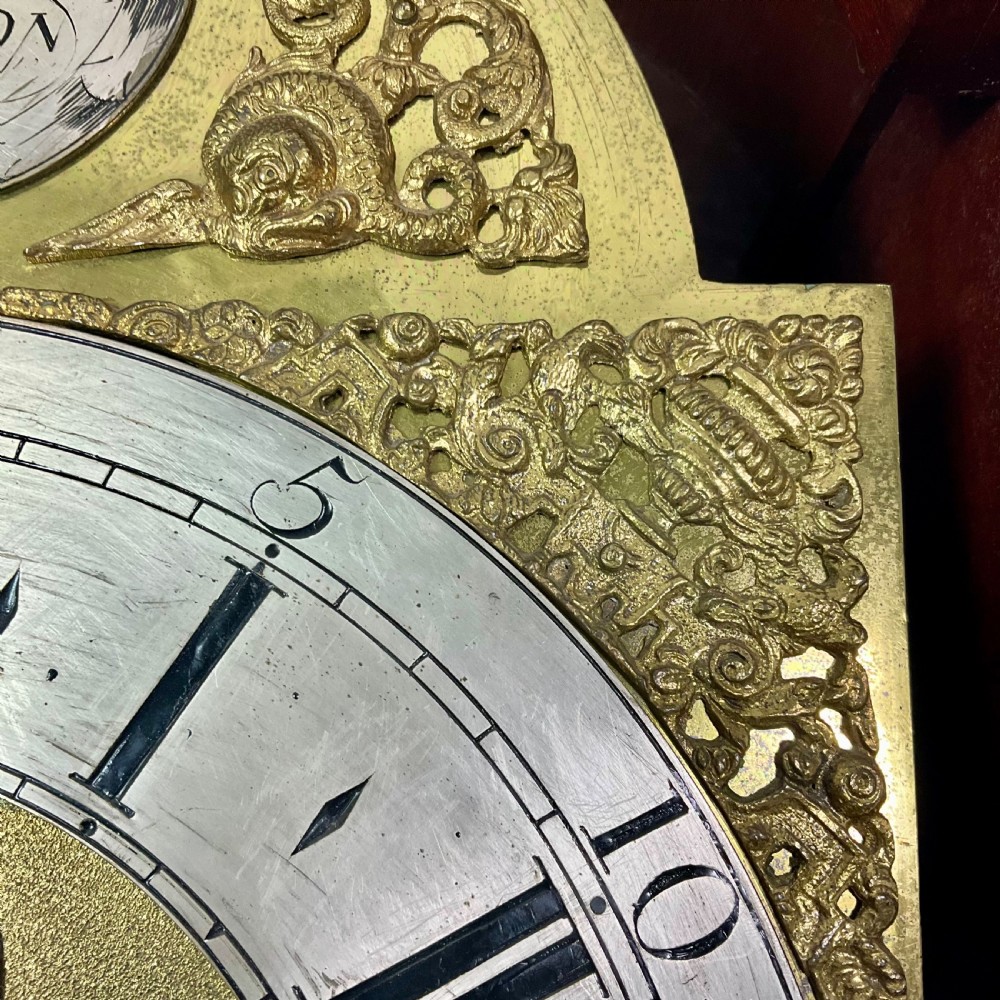 An 18th-century Georgian mahogany longcase clock featuring an arched brass dial with an engraved maker silvered boss and brass spandrels. View VI