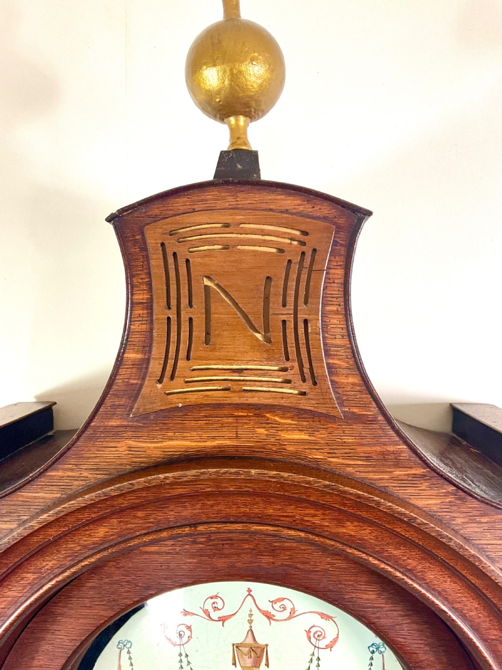 A Georgian oak longcase clock featuring a swan-neck pediment, brass ball finials, fluted columns, and a painted arch dial displaying Roman numerals. View II