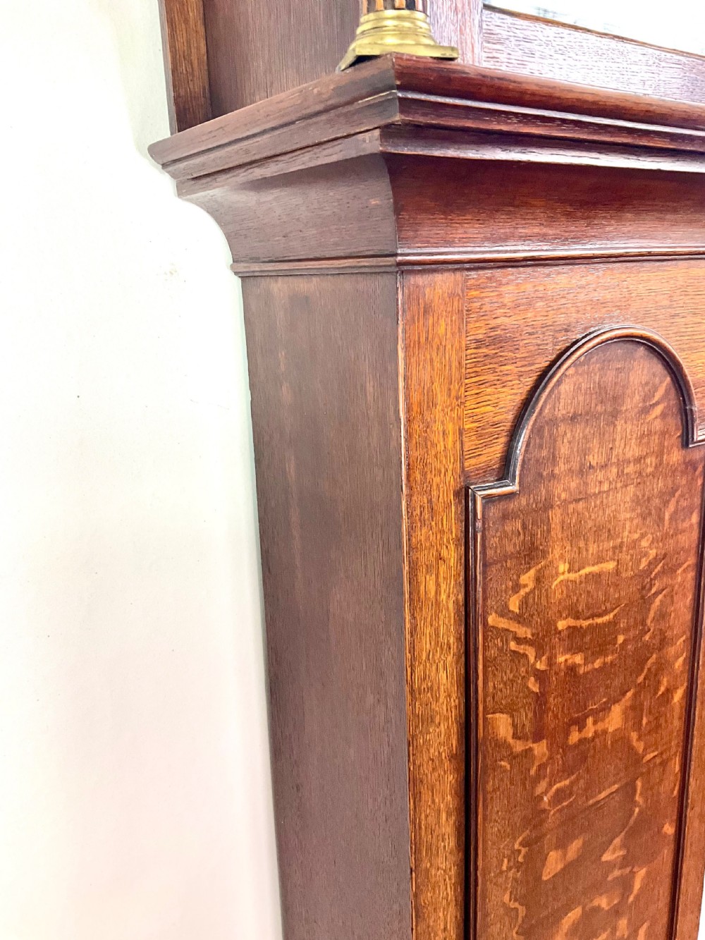 A Georgian oak longcase clock featuring a swan-neck pediment, brass ball finials, fluted columns, and a painted arch dial displaying Roman numerals. View V