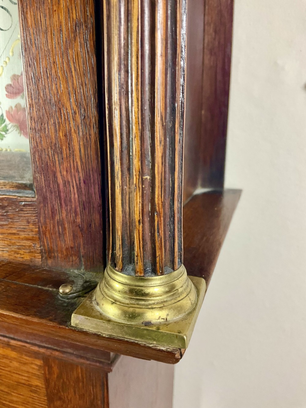 A Georgian oak longcase clock featuring a swan-neck pediment, brass ball finials, fluted columns, and a painted arch dial displaying Roman numerals. View XI