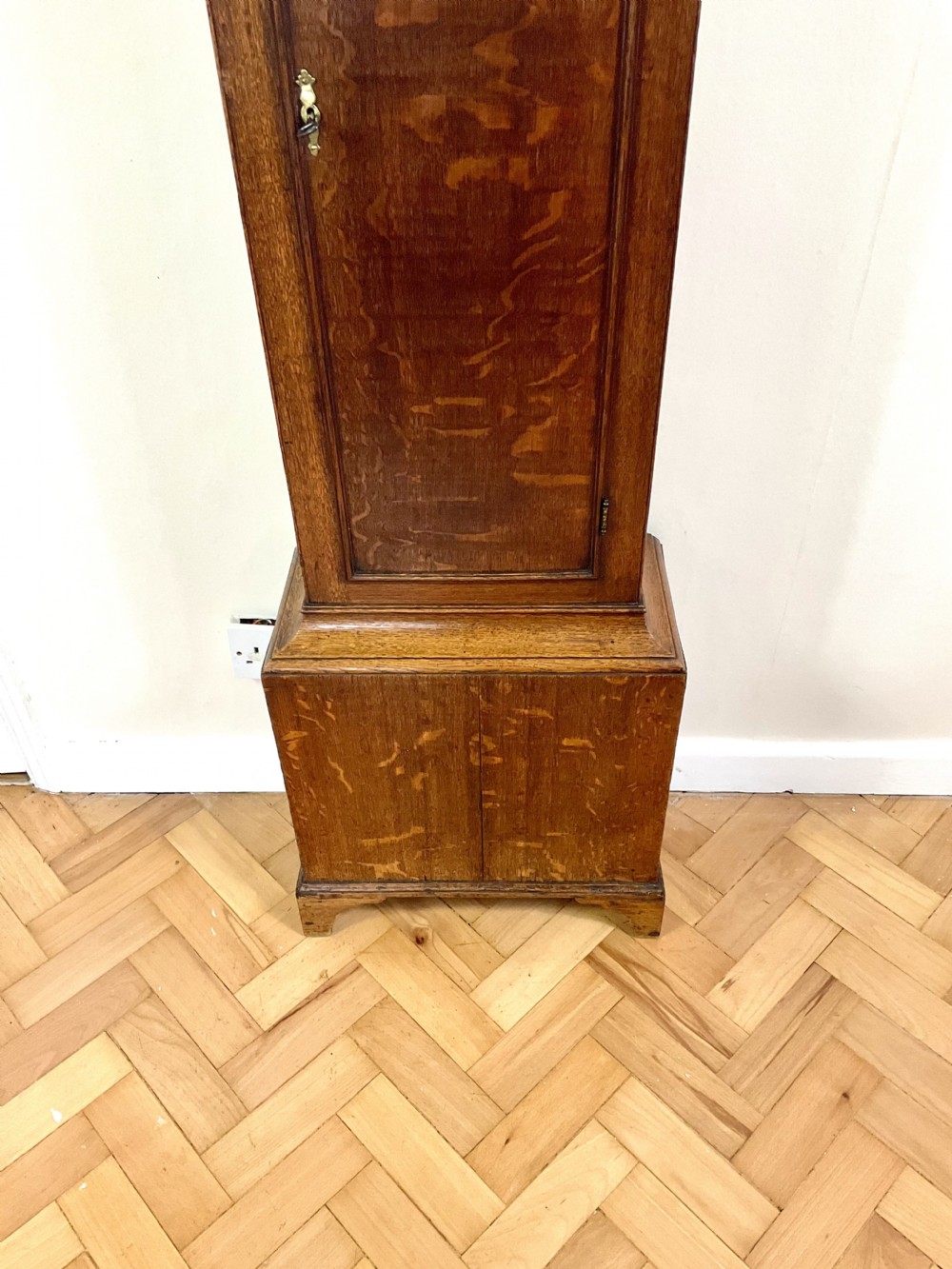 A Georgian oak longcase clock featuring a swan-neck pediment, brass ball finials, fluted columns, and a painted arch dial displaying Roman numerals. View XII