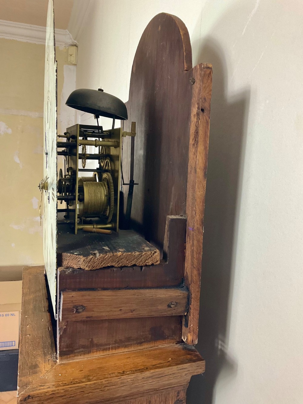 An antique Georgian longcase clock hood crafted from light oak with an arched glass door, brass-capped side columns, and a painted white dial with Roman numerals. View VI