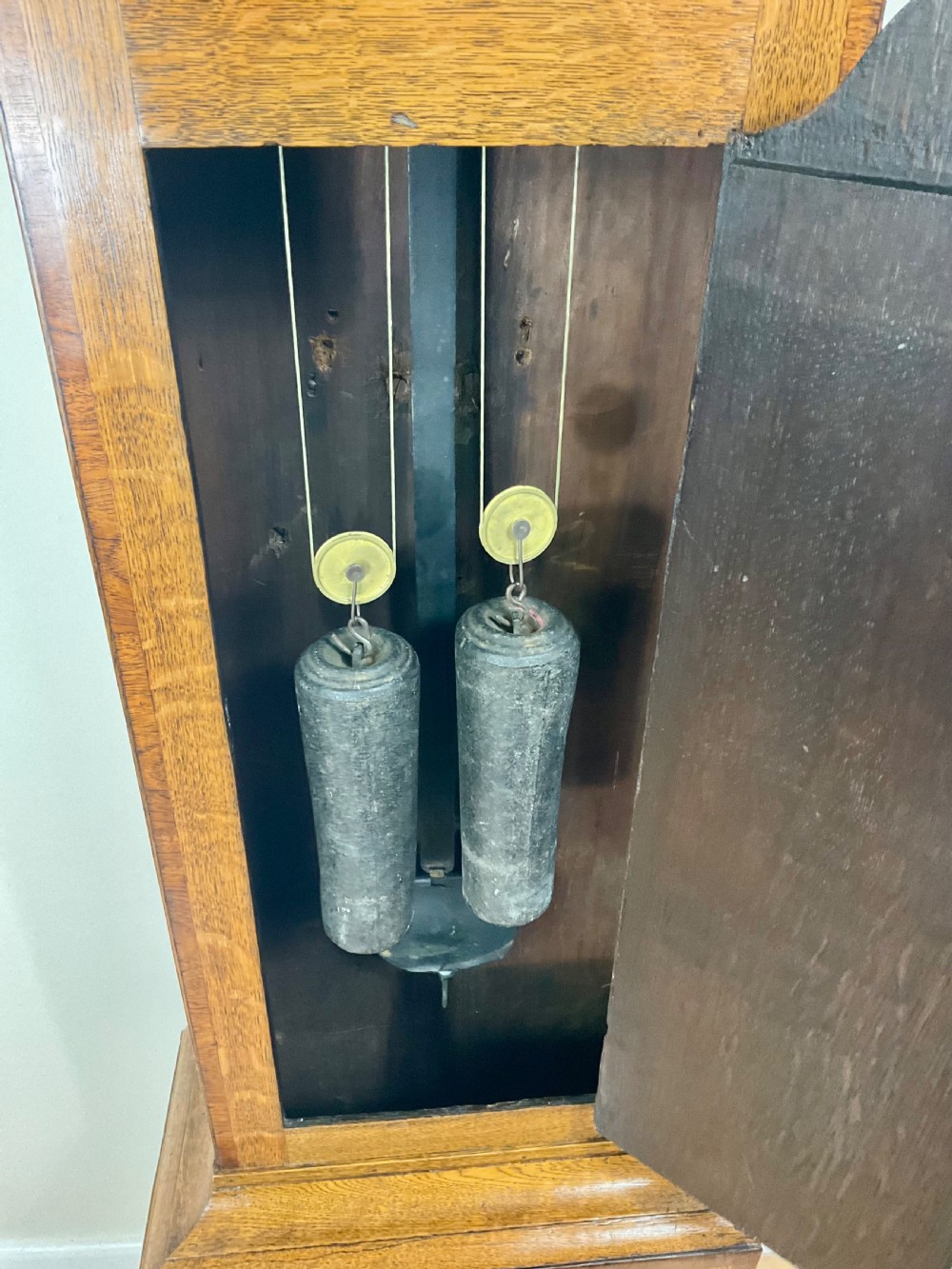 An antique Georgian longcase clock hood crafted from light oak with an arched glass door, brass-capped side columns, and a painted white dial with Roman numerals. View VIII