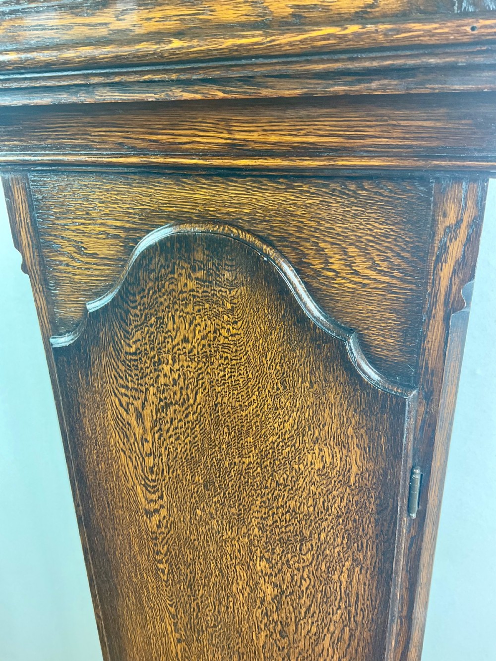 A dark oak grandmother longcase clock featuring an arched hood, clear glass door, and a brass dial with Roman numerals. View II