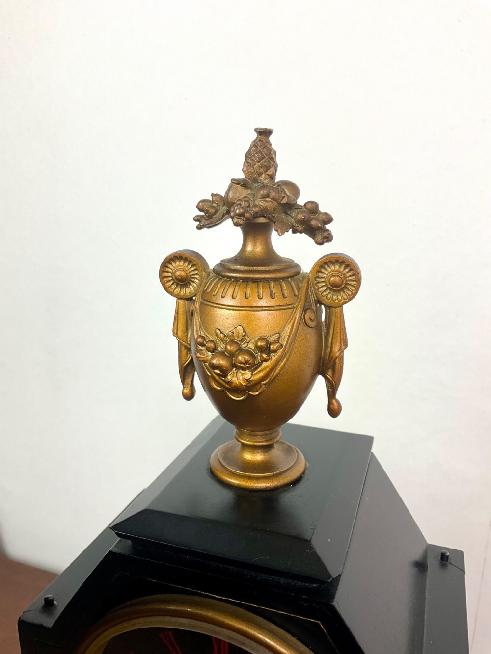 A black slate Egyptian Revival mantel clock featuring a central dial with red Roman numerals, flanked by two gilt bronze sphinxes and topped with a gilt urn finial. View VI