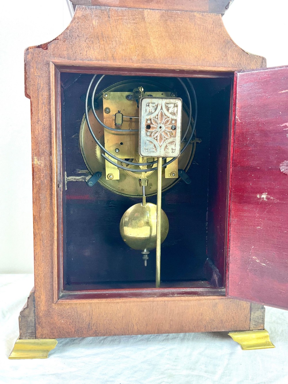An Edwardian inlaid mahogany mantel clock featuring a circular dial, brass bezel, floral marquetry detailing, and brass bracket feet. View III