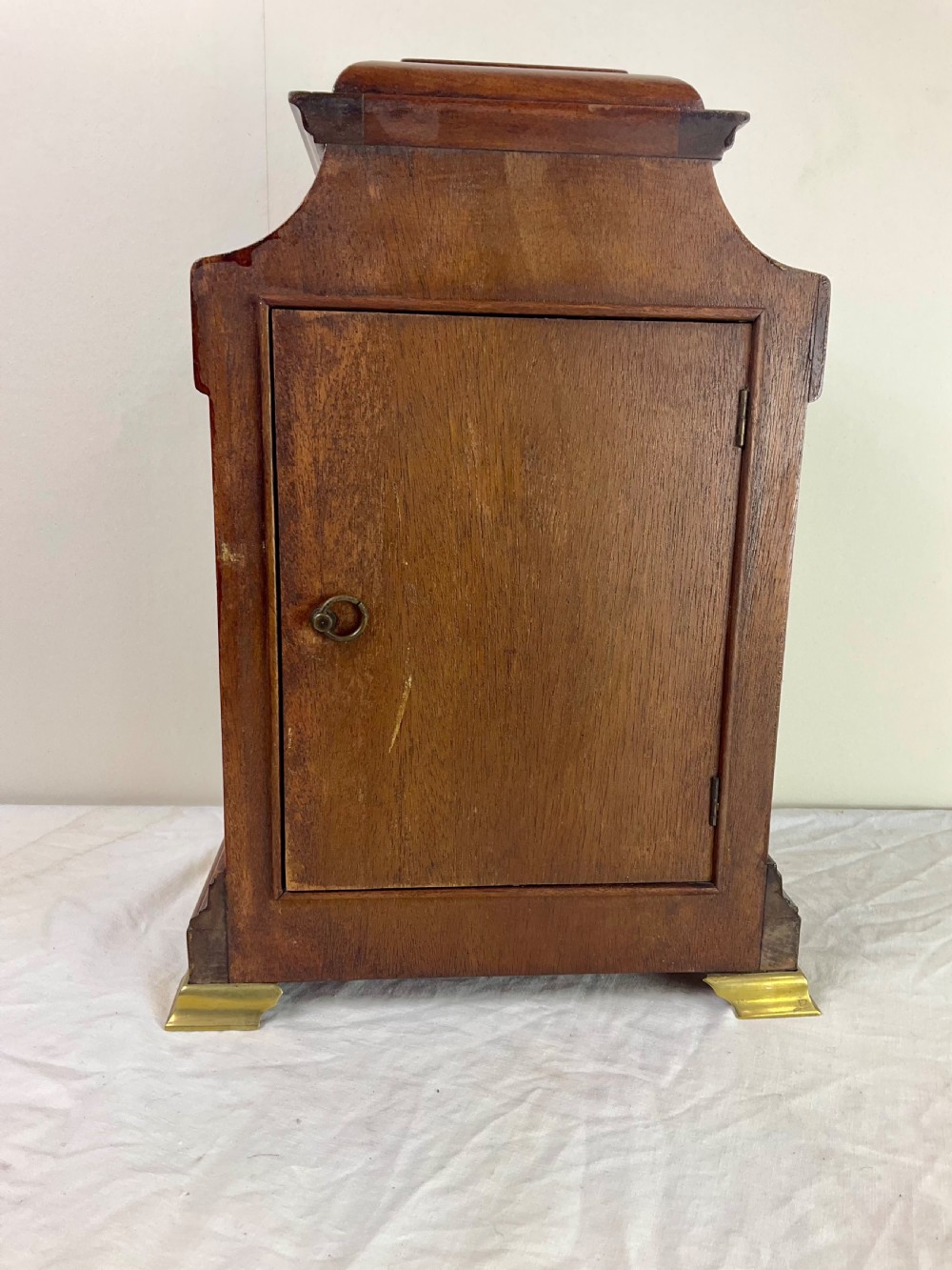 An Edwardian inlaid mahogany mantel clock featuring a circular dial, brass bezel, floral marquetry detailing, and brass bracket feet. View V