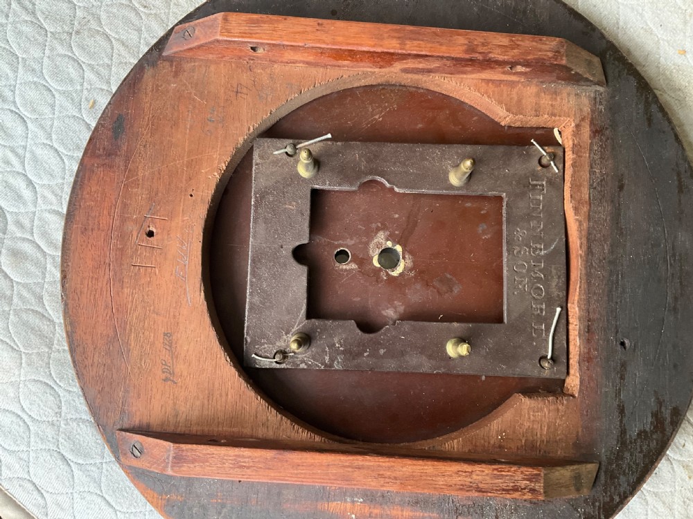 An early nineteenth-century circular wall clock featuring a mahogany surround, brass bezel, and painted cream dial with black Roman numerals. View VI