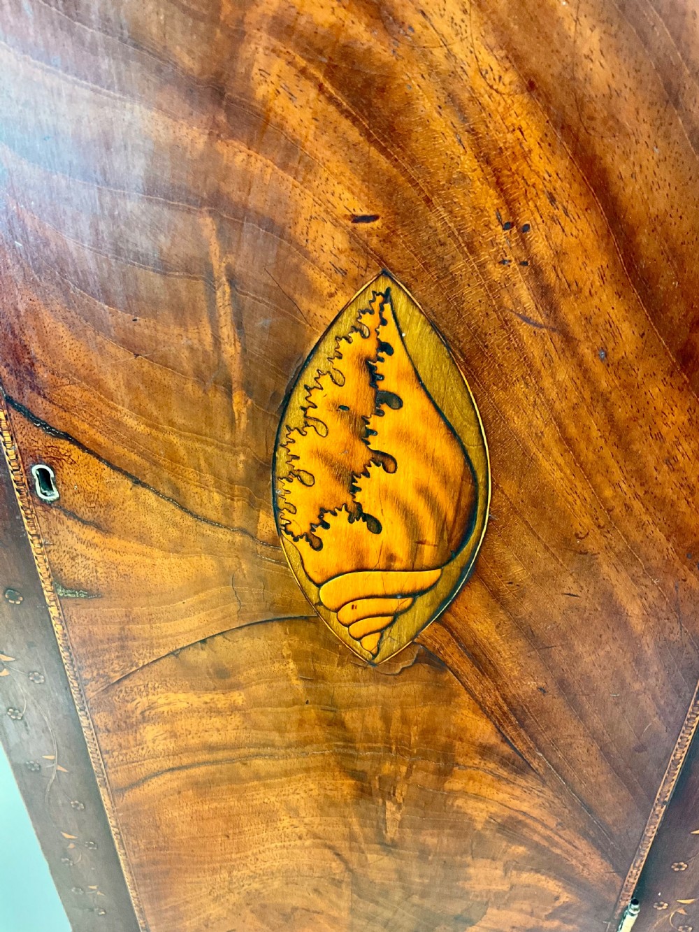 A Georgian mahogany longcase clock featuring a swan-neck pediment, painted dial, shell marquetry inlay, and reeded side columns. View VII