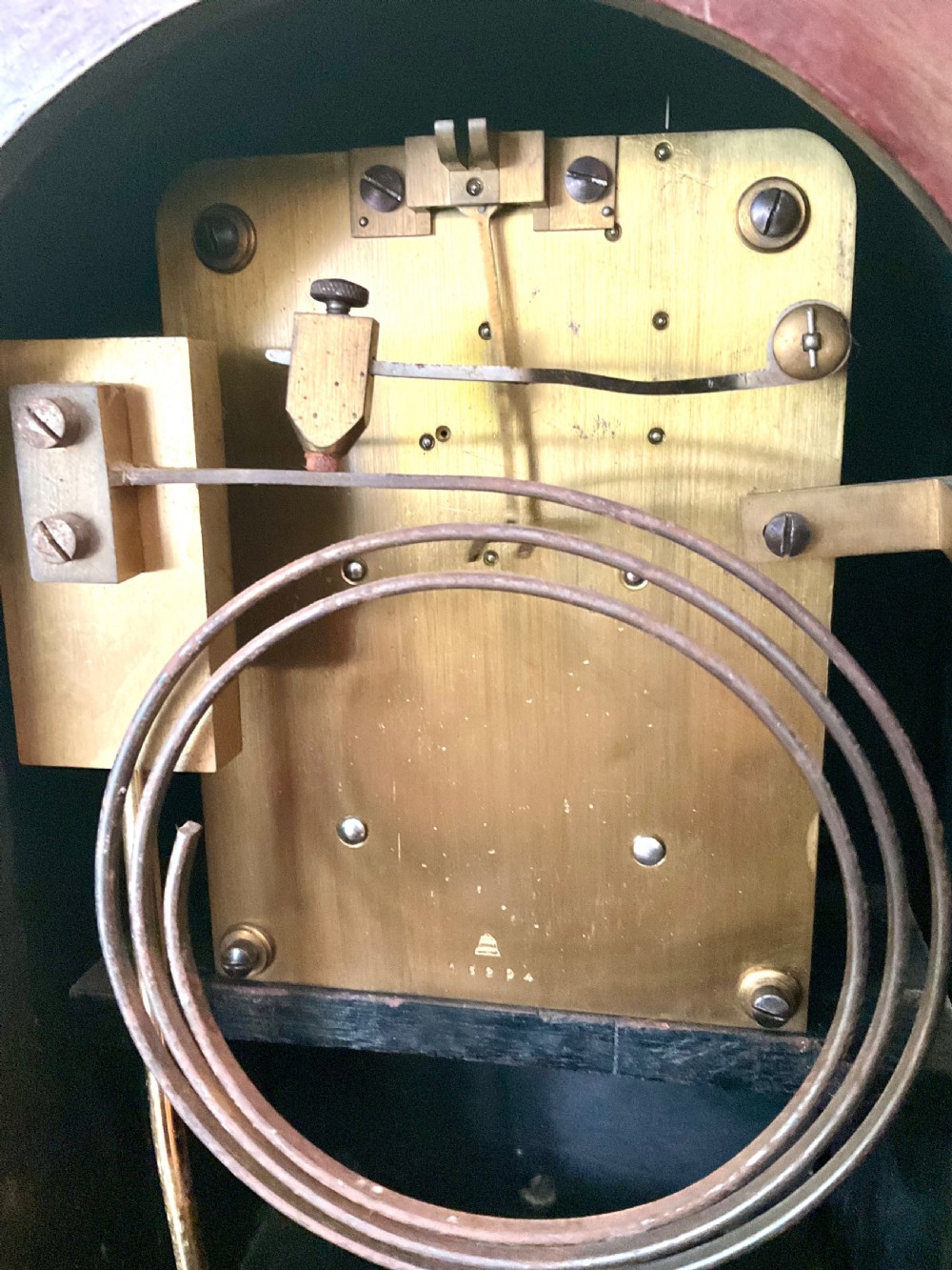 An English mahogany bracket clock featuring an arched top, white dial with Roman numerals, brass bezel, geometric marquetry inlay, and four brass ball feet. View IX