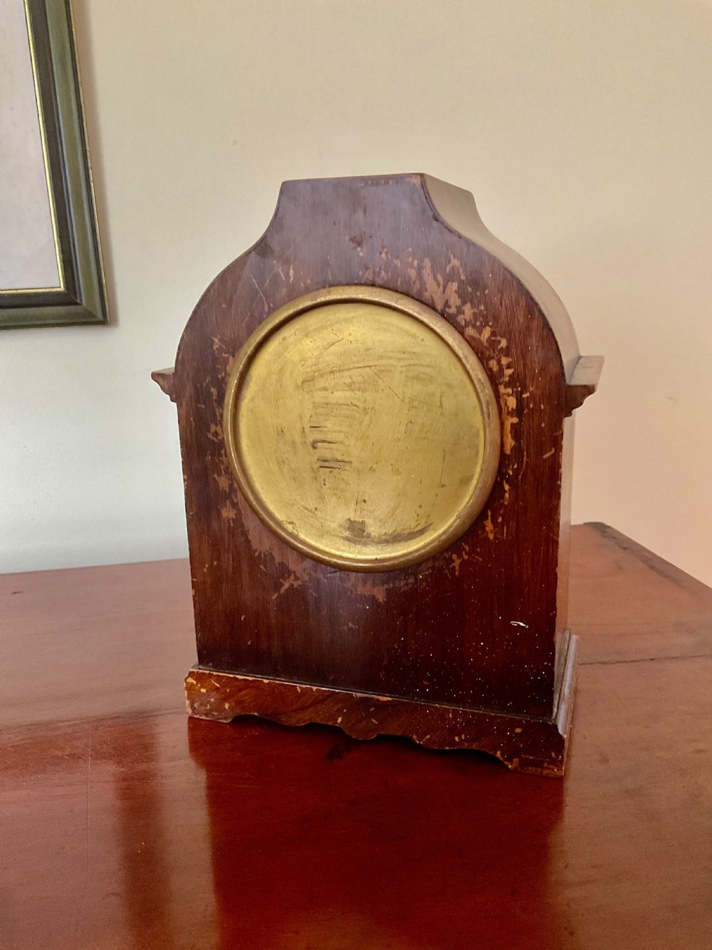 A small figured walnut mantel clock featuring an arched timber case, a brass-framed dial, and black Roman numerals. View VII
