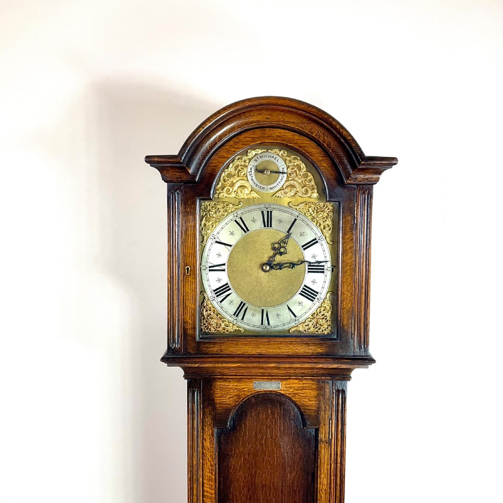 An antique dark oak longcase grandfather clock featuring an arched hood, brass dial with silvered chapter ring, and a tall panelled trunk. View VIII