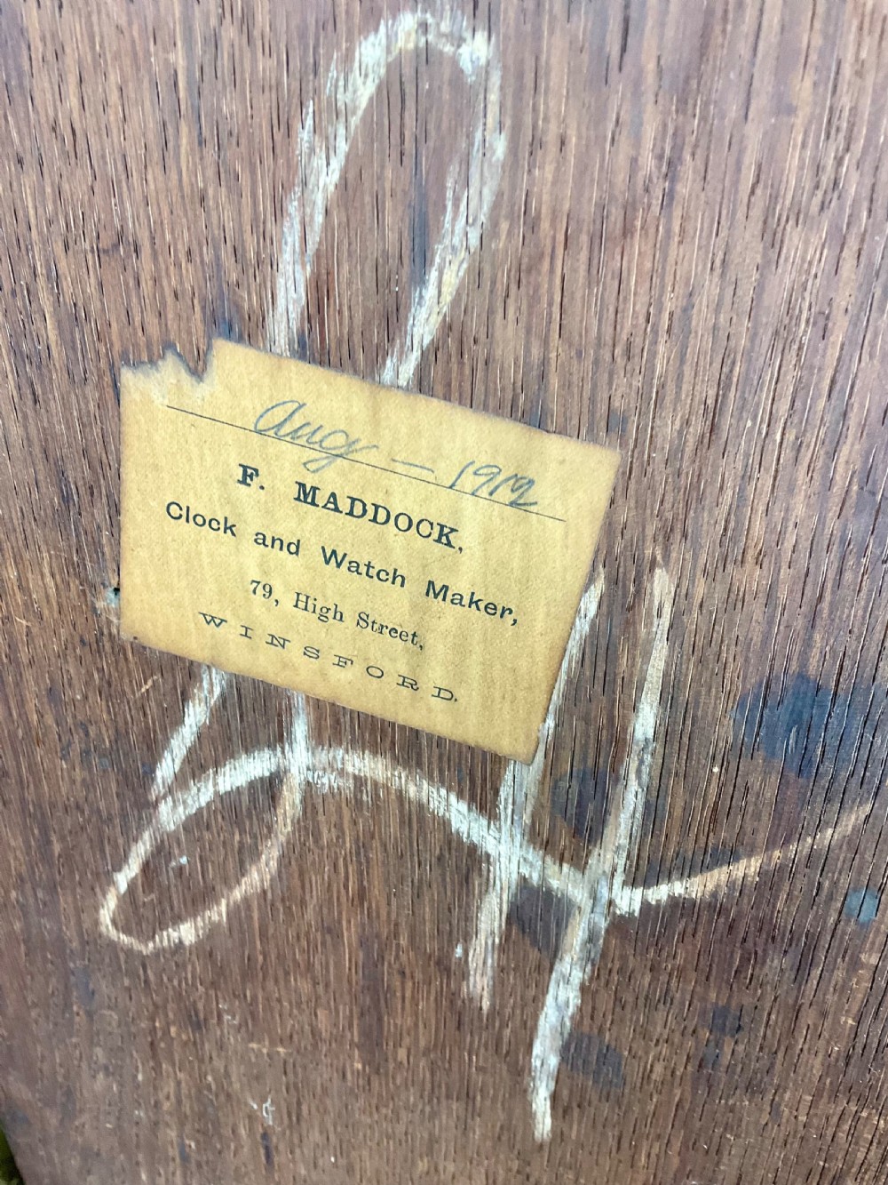 A tall Georgian dark oak longcase clock featuring an engraved brass square dial, fluted quarter-columns, and a shaped trunk door. View XI