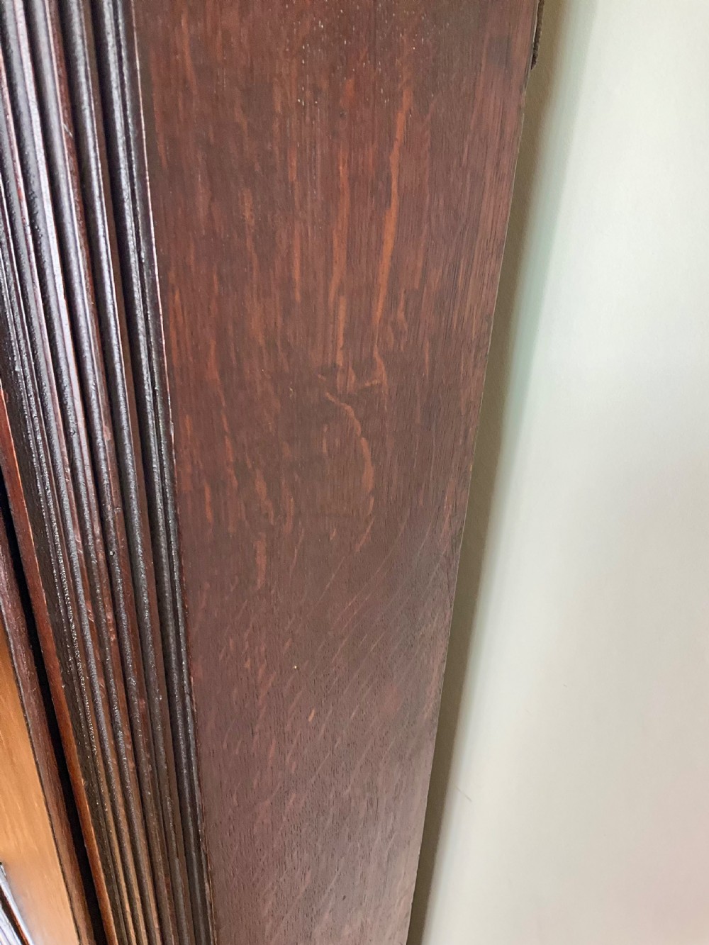 A tall Georgian dark oak longcase clock featuring an engraved brass square dial, fluted quarter-columns, and a shaped trunk door. View XVI
