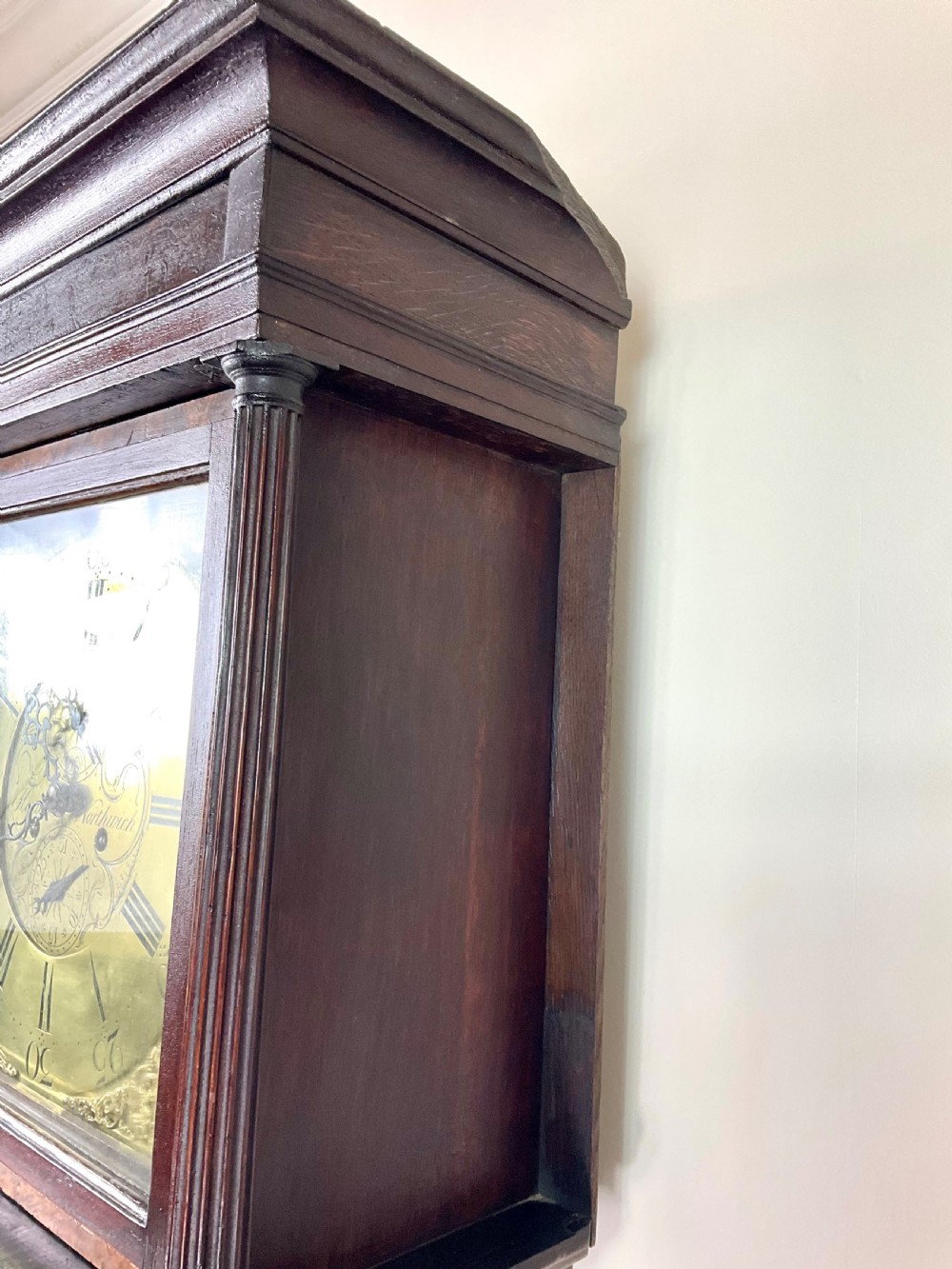 A tall Georgian dark oak longcase clock featuring an engraved brass square dial, fluted quarter-columns, and a shaped trunk door. View XVII