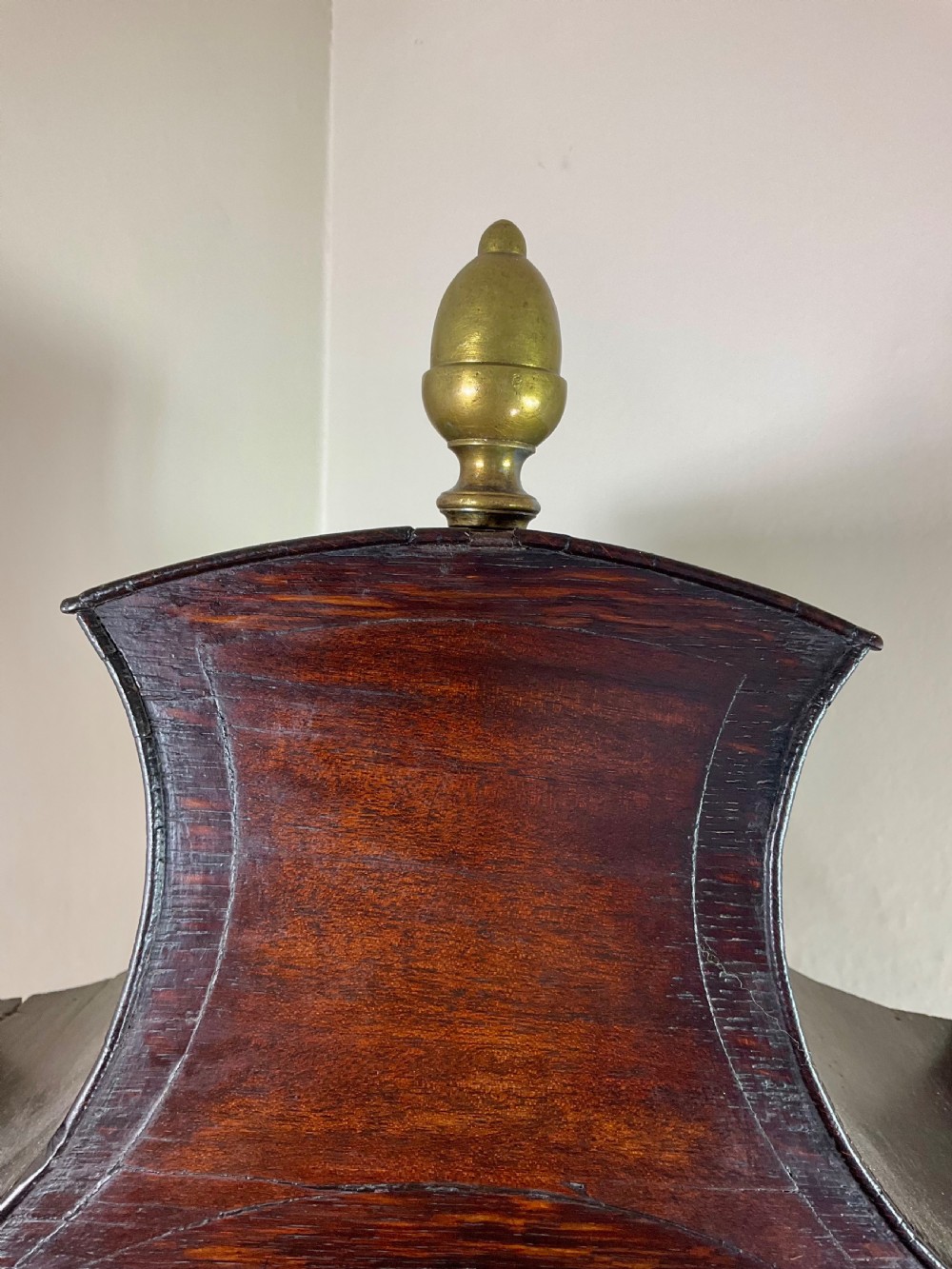 A dark oak Georgian longcase clock featuring a painted arched dial with Roman numerals and three brass urn finials on the bonnet. View III